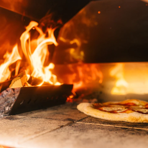 Pizza cooking in Fontana Riviera Wood Pizza Oven in Stainless Steel Including Trolley