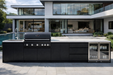 Modern outdoor kitchen with black appliances in a luxurious home setting